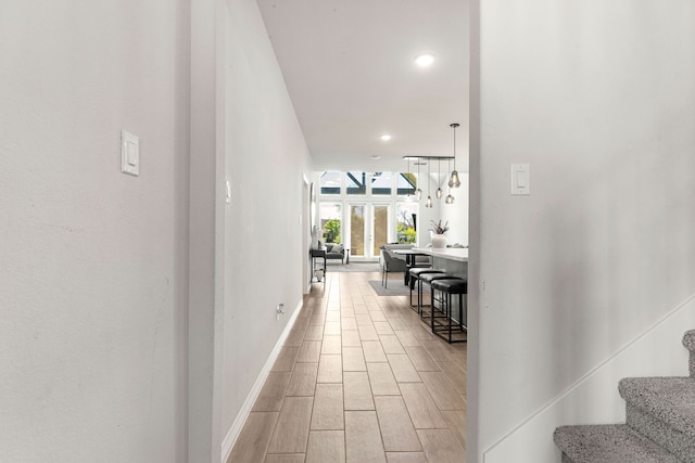 hall featuring light wood-style flooring, baseboards, recessed lighting, and stairs