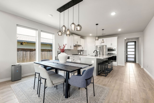 dining room with recessed lighting, light wood finished floors, and baseboards