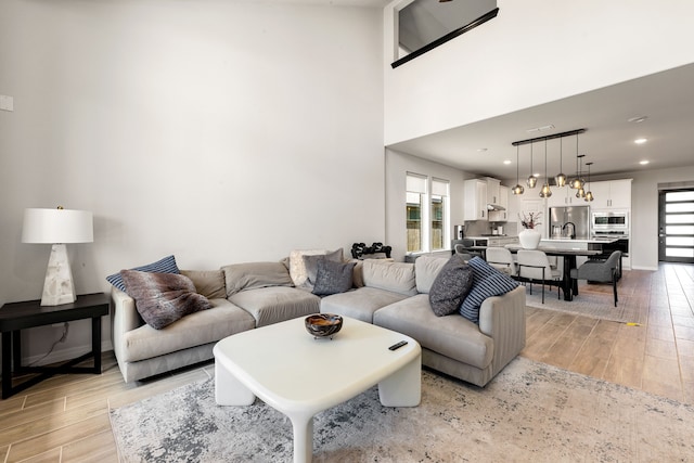 living area with recessed lighting, light wood-style floors, and baseboards