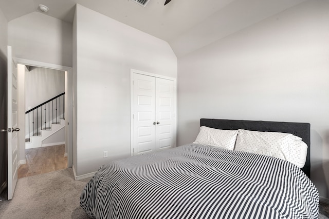 carpeted bedroom featuring baseboards, vaulted ceiling, and a closet