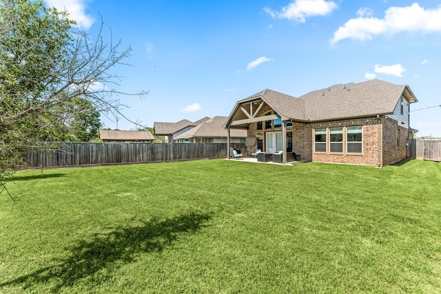 rear view of house featuring a fenced backyard, a yard, a patio, an outdoor hangout area, and brick siding