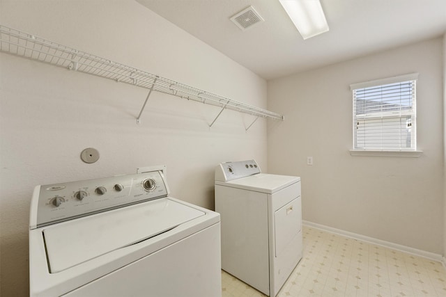 washroom featuring washing machine and dryer, light flooring, and baseboards