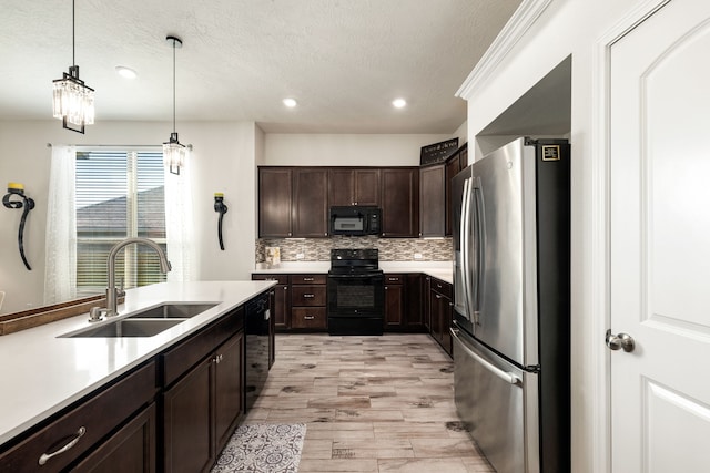 kitchen featuring a sink, black appliances, light wood-type flooring, dark brown cabinetry, and pendant lighting