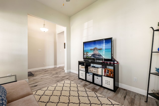 living area with baseboards, a ceiling fan, and wood finished floors