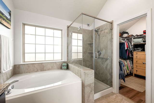 bathroom with a garden tub, a wealth of natural light, a shower stall, and a walk in closet