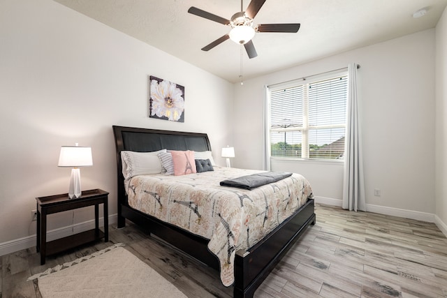 bedroom with ceiling fan, baseboards, and light wood-type flooring