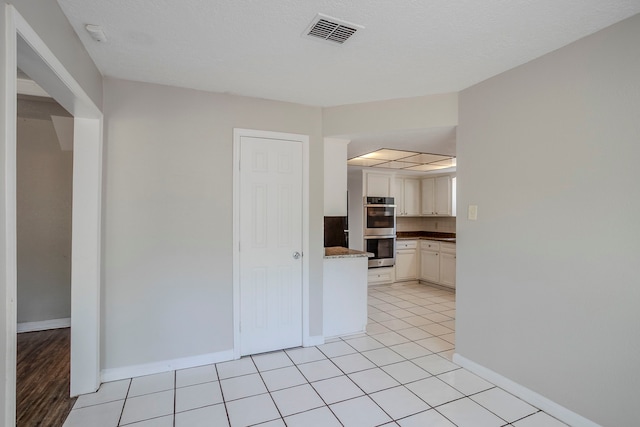 10610 Dunbrook Dr, Houston, TX 77070 - kitchen featuring dark countertops, stainless steel double oven, baseboards, white cabinetry, and visible vents