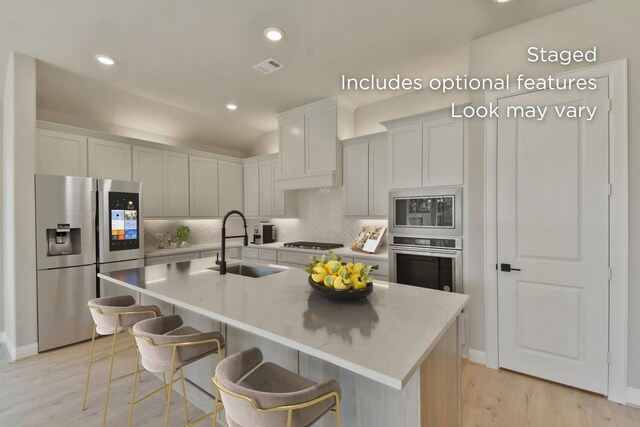 13136 Soaring Forest Dr, Conroe, TX 77302 - kitchen featuring stainless steel appliances, a sink, tasteful backsplash, light wood-type flooring, and a center island with sink