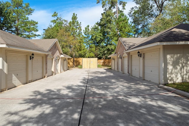 6607 Lake Woodlands Dr Unit 124, The Woodlands, TX 77382 - view of side of property featuring community garages, roof with shingles, fence, an outbuilding, and brick siding