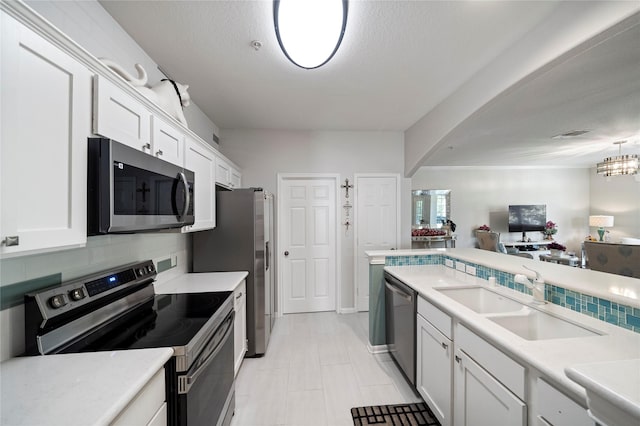 6607 Lake Woodlands Dr Unit 124, The Woodlands, TX 77382 - kitchen with appliances with stainless steel finishes, a sink, white cabinetry, light countertops, and arched walkways