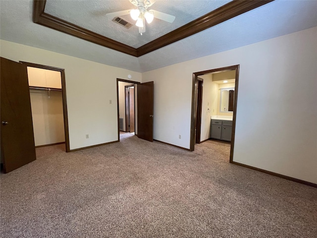 unfurnished bedroom with a tray ceiling, visible vents, baseboards, a textured ceiling, and light colored carpet