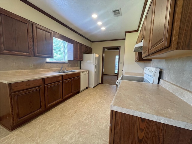 kitchen featuring a sink, visible vents, white appliances, crown molding, and light countertops