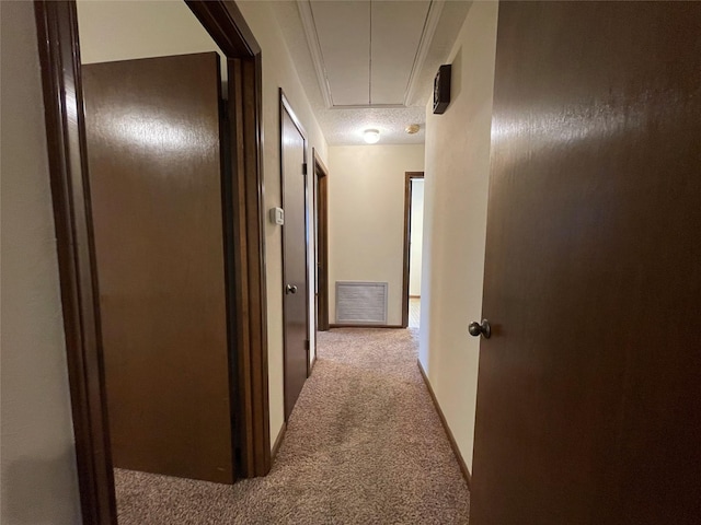 corridor with attic access, carpet, and visible vents