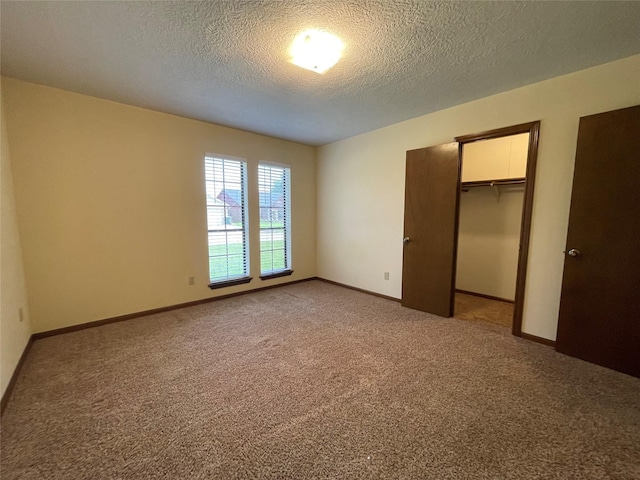 unfurnished bedroom with light carpet, a closet, a textured ceiling, and baseboards