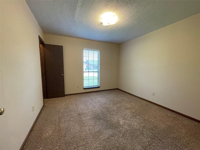 carpeted empty room with a textured ceiling and baseboards