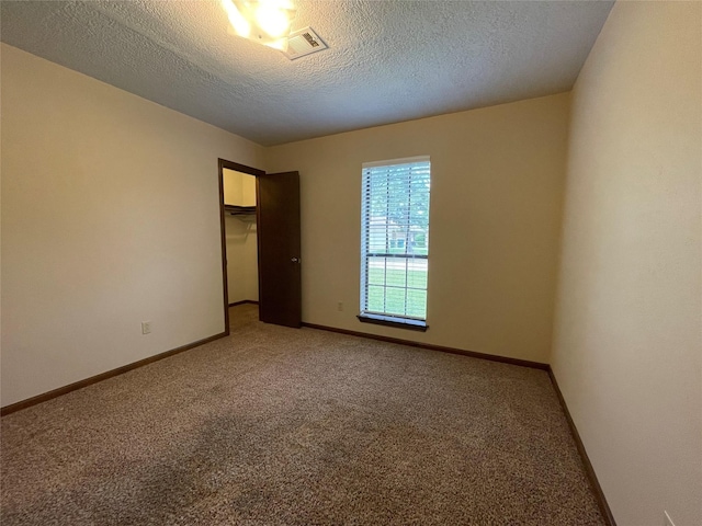 unfurnished room with light colored carpet, baseboards, a textured ceiling, and visible vents