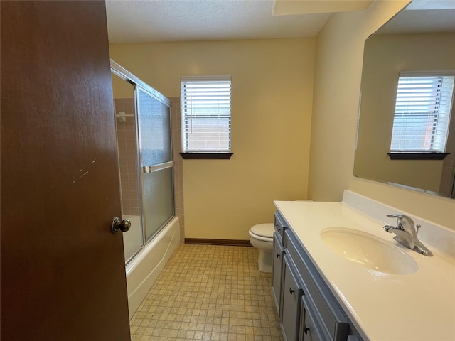bathroom with tile patterned floors, enclosed tub / shower combo, toilet, vanity, and baseboards