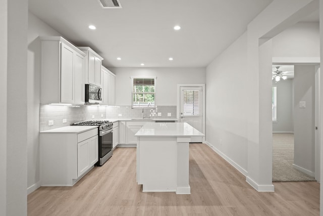 kitchen with tasteful backsplash, light wood-type flooring, ceiling fan, light countertops, and appliances with stainless steel finishes