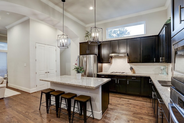 kitchen with stainless steel appliances, a kitchen breakfast bar, ornamental molding, and a notable chandelier