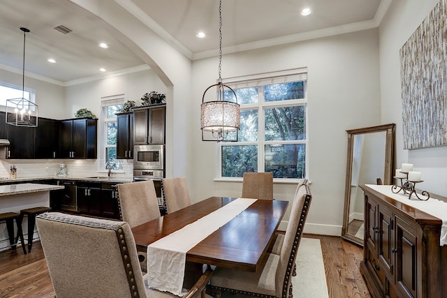 dining space featuring dark wood-type flooring, visible vents, an inviting chandelier, crown molding, and arched walkways