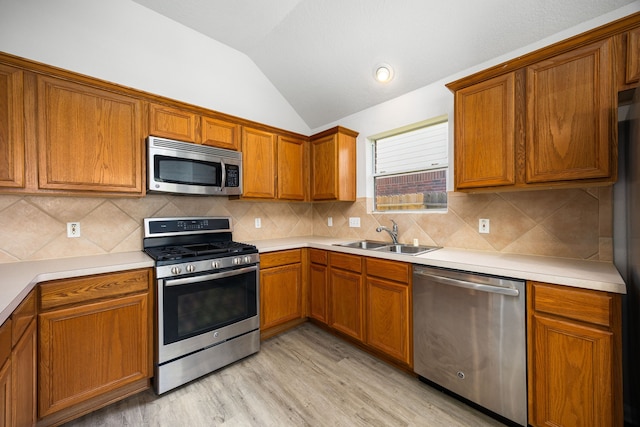 6723 Cypress Glades Dr, Katy, TX 77449 - kitchen with lofted ceiling, stainless steel appliances, a sink, light wood-type flooring, and brown cabinetry