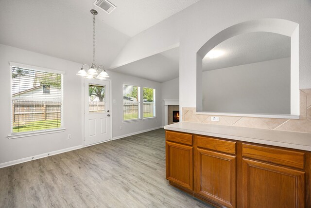 6723 Cypress Glades Dr, Katy, TX 77449 - kitchen with lofted ceiling, light countertops, a tiled fireplace, and visible vents