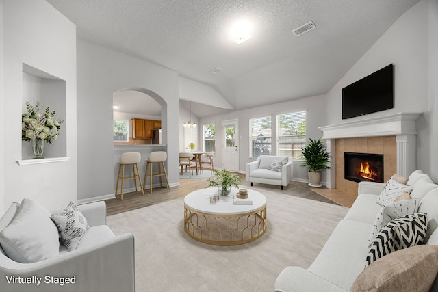 6723 Cypress Glades Dr, Katy, TX 77449 - living room featuring light wood-style floors, arched walkways, a fireplace, lofted ceiling, and visible vents
