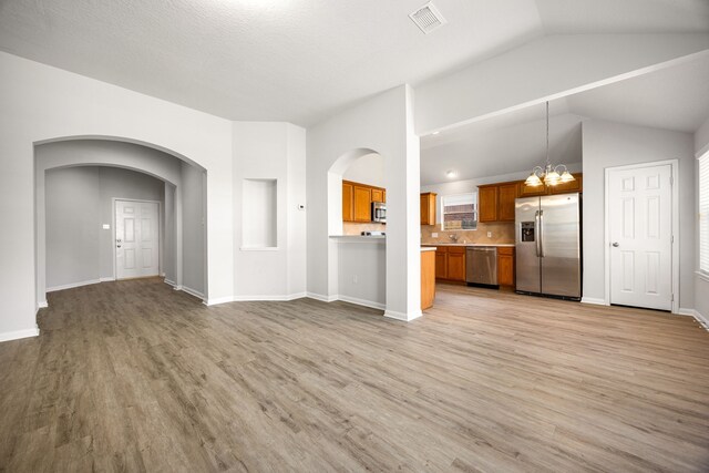6723 Cypress Glades Dr, Katy, TX 77449 - unfurnished living room featuring lofted ceiling, arched walkways, visible vents, and light wood finished floors