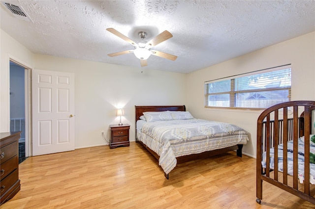 bedroom featuring baseboards, visible vents, a textured ceiling, and light wood-style floors