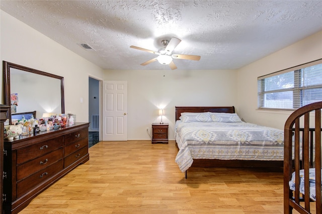 bedroom featuring light wood-type flooring, visible vents, and a textured ceiling