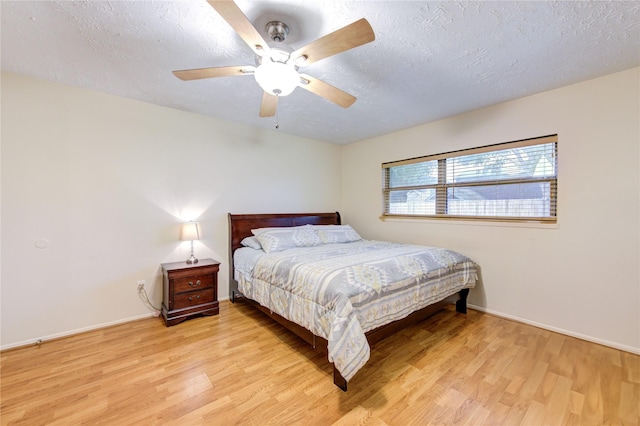 bedroom featuring light wood-type flooring, baseboards, and a textured ceiling