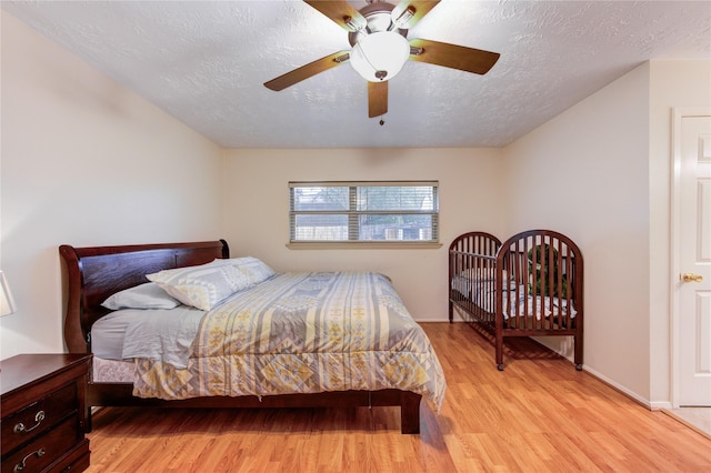 bedroom with light wood-style flooring, a textured ceiling, and a ceiling fan
