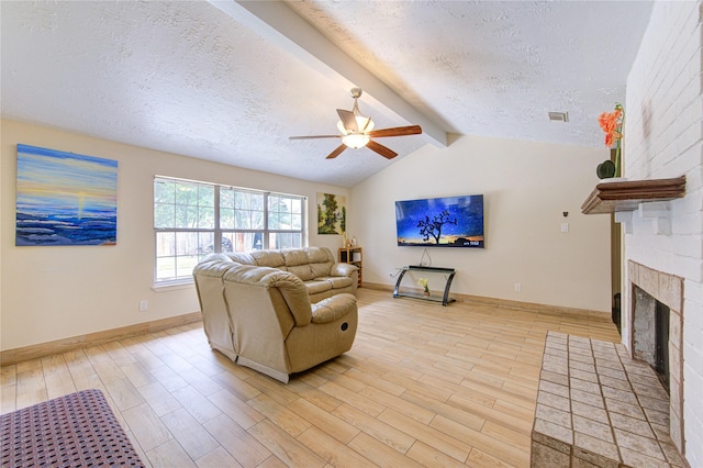 living room featuring visible vents, a fireplace, light wood-style flooring, a textured ceiling, and ceiling fan