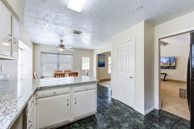 kitchen with visible vents, a ceiling fan, baseboards, a peninsula, and white cabinetry