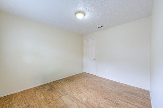 empty room featuring baseboards, visible vents, a textured ceiling, and light wood-style floors