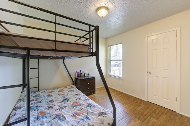bedroom featuring wood finished floors, a textured ceiling, and baseboards