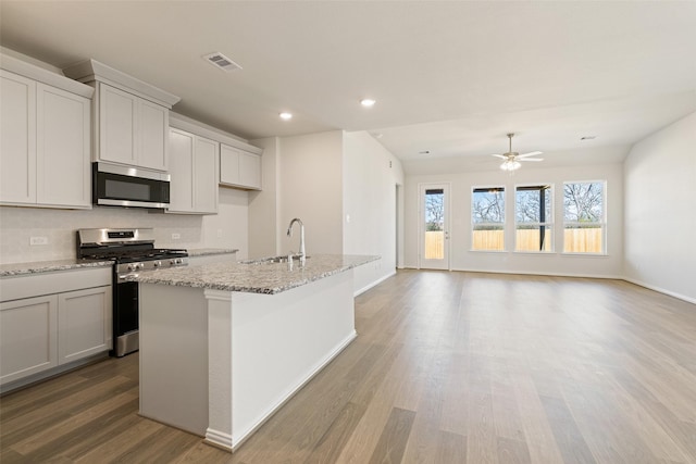 2014 Sunflower Ct, Sugar Land, TX 77498 - kitchen featuring stainless steel appliances, a sink, light wood-type flooring, an island with sink, and decorative backsplash
