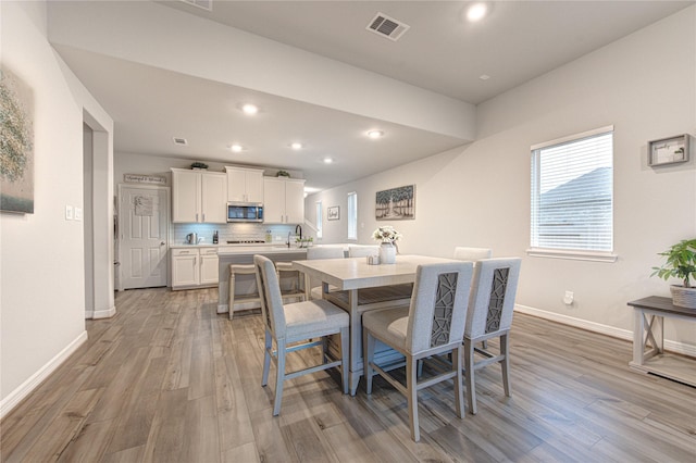 dining area featuring light wood-style flooring, visible vents, and baseboards