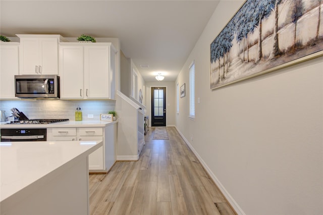 kitchen with tasteful backsplash, light wood-type flooring, stainless steel appliances, light countertops, and white cabinetry