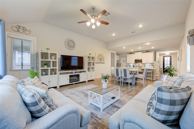 living room featuring recessed lighting, lofted ceiling, light wood finished floors, visible vents, and a ceiling fan