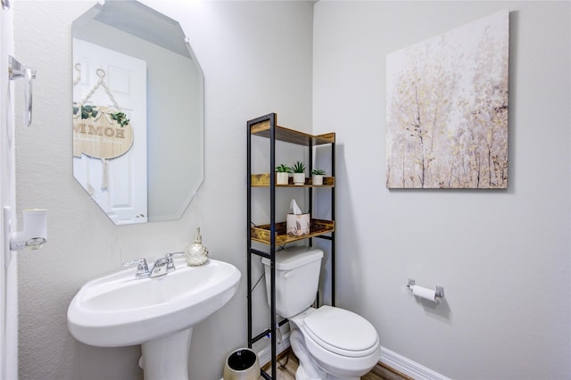 bathroom featuring baseboards, a sink, and toilet