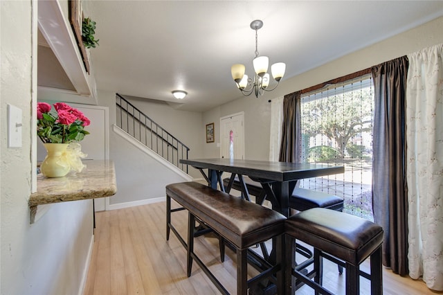 dining space featuring stairs, a chandelier, light wood finished floors, and baseboards