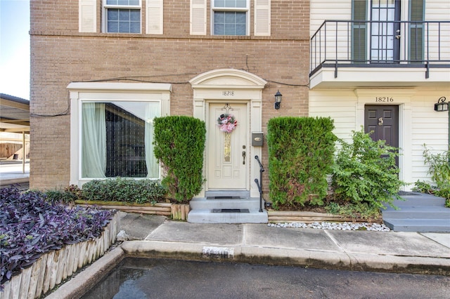 property entrance with brick siding and a balcony