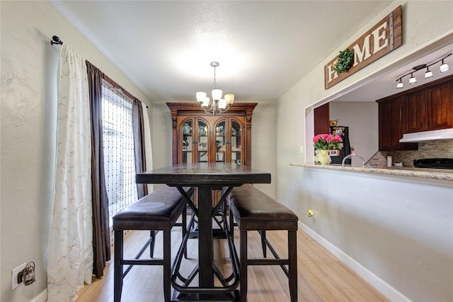 dining room featuring baseboards, a chandelier, and light wood-type flooring