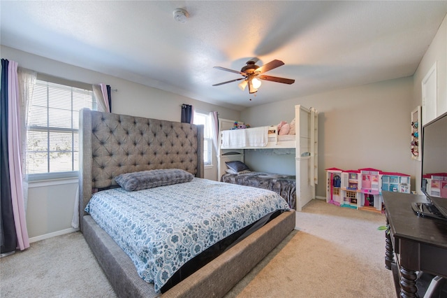 bedroom featuring light colored carpet, ceiling fan, baseboards, and multiple windows