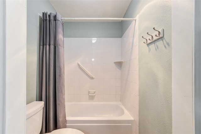 bathroom featuring shower / tub combo with curtain, toilet, and a textured wall