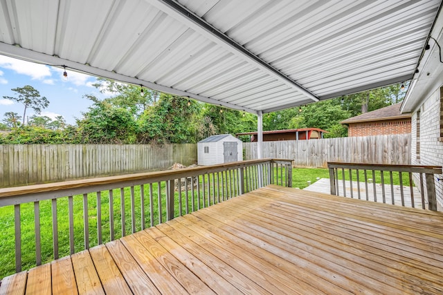 deck with a storage unit, a fenced backyard, a lawn, and an outdoor structure