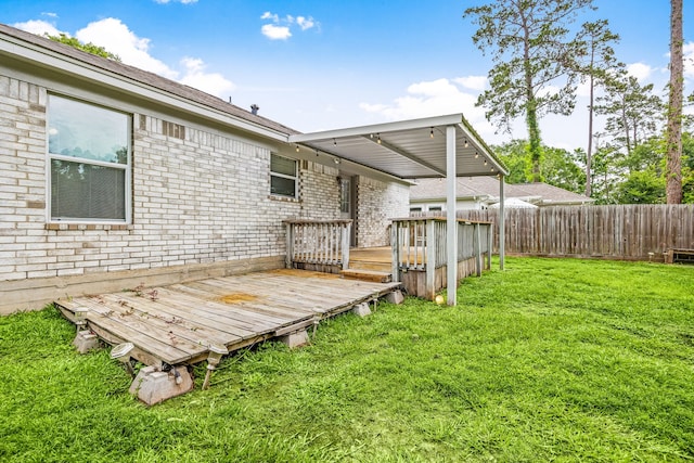 back of property with fence, a lawn, a deck, and brick siding