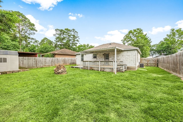view of yard featuring central AC, a fenced backyard, an outbuilding, an outdoor fire pit, and a storage shed