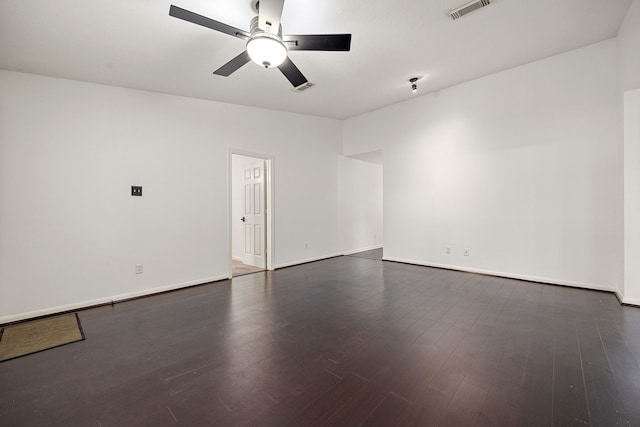 unfurnished room with visible vents, a ceiling fan, dark wood finished floors, and baseboards
